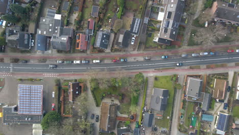 Top-down-aerial-of-cars-driving-over-a-calm-road-through-a-beautiful-small-town