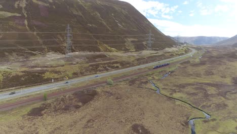 Left-to-Right-aerial-shot-over-the-Highland-Train-Line-looking-south-with-a-local-train-passing-through-frame
