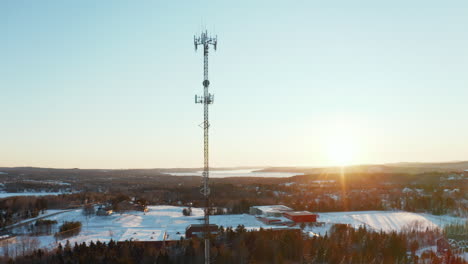 Aerial-view-of-a-cell-phone-tower-in-a-snowy-suburban-neighborhood-at-sunset