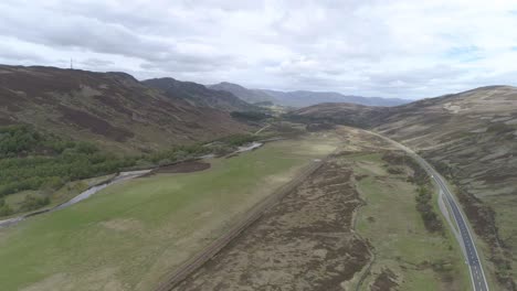 Left-to-right-aerial-shot-above-the-main-road-A9-and-railway-near-Dalwhinnie-in-Scottish-Highlands