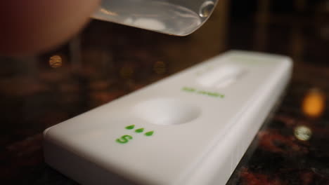 Slow-motion-pouring-drops-of-solution-into-a-COVID-19-rapid-antigen-test