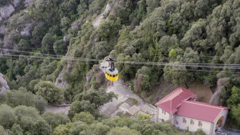Yellow-cable-car-going-up-to-the-monastery-on-the-Montserrat-mountain-in-Catalonia,-Spain