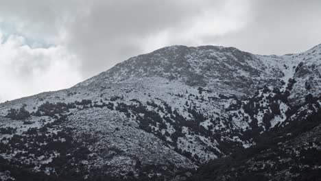 Aerial-drone-view-of-white-snowy-mountain-peak,-Sardinia-landscape,-cloudy-day,-forward
