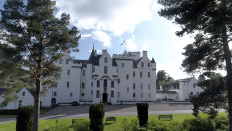Low-aerial-pull-back,-parallax-shot-of-Blair-Castle-flying-the-Scottish-Flag-of-the-Saltire