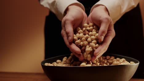 Hands-scooping-bowl-full-of-tasty-hazelnuts