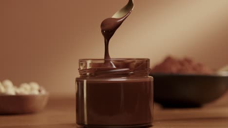 Chocolate,-hazelnut-cream-scooping-with-golden-spoon-on-table-slowmotion-shot