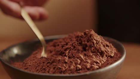 Closeup-shot-of-spoon-scooping-cocoa-powder-from-bowl