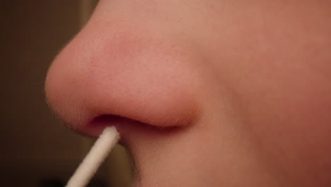 Close-up-of-a-child's-nose-being-swabbed-for-a-covid-19-at-home-rapid-antigen-test