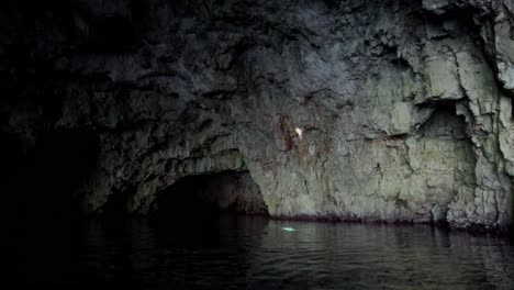 Mysterious-atmosphere-inside-a-sea-cave-with-a-beam-of-light-reflecting-on-water-and-projecting-against-a-rocky-wall,-Vis-island,-Adriatic-Sea,-Croatia