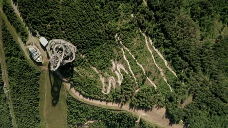 Aerial-zoom-in-drone-point-of-view-of-a-sky-walk-tower-attraction-Dolni-Morava,-Czech-Republic-and-a-nearby-MTB-bicycle-trail