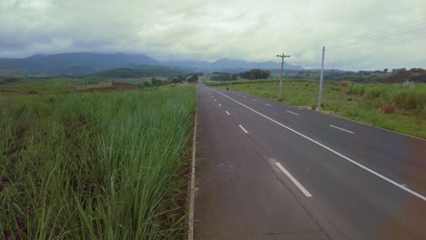 A-jib-shot-of-an-empty-road,-surrounded-by-tall-grass