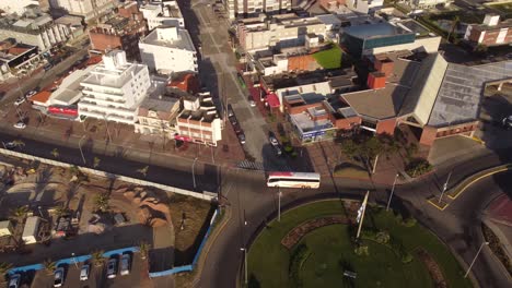 Luftaufnahmen-Von-Oben-Nach-Unten-Des-Tourbusses,-Der-Im-Kreisverkehr-Der-Stadt-Punta-Del-Este-Im-Sonnenlicht,-Uruguay,-Fährt