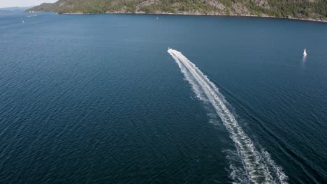Boat-speeds-away-straight-into-the-distance-while-the-drone-ascends-up-in-4K