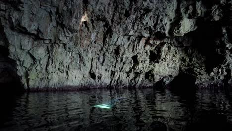 Mysterious-scene-inside-a-sea-cave-with-a-ray-of-light-coming-down-from-the-ceiling-and-reflecting-on-a-wall,-Vis-island,-Adriatic-Sea,-Croatia