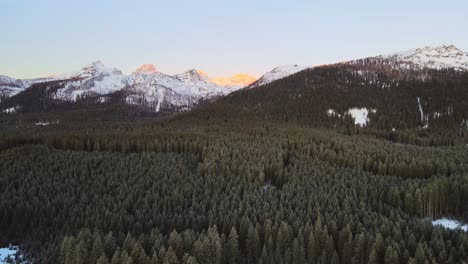 Nature-captured-with-a-drone-with-landscape-and-mountains-covered-in-snow-at-golden-hour-at-sunrise-with-beautiful-forest-and-surrounding-hills-captured-in-Slovenia-above-forest-Pokljuka-in-4k
