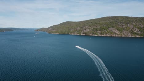 Boat-speeds-away-into-the-distance-in-a-fjord-on-a-sunny-day