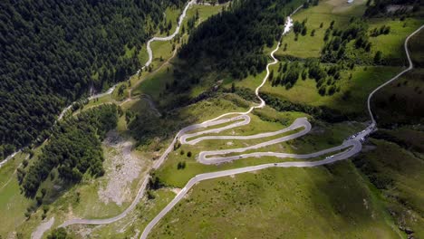 Top-down-aerial-footage-from-a-winding-road-in-the-Austrian-Alps,-while-motorcycles-and-cars-are-passing-through-the-turns