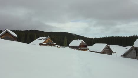 Mit-Einer-Drohne-Eingefangene-Natur-Mit-Der-Landschaft,-Schneebedeckte-Berge-Zur-Goldenen-Stunde-Bei-Sonnenaufgang-Mit-Wald-Und-Umliegenden-Hügeln,-Eingefangen-In-Slowenien-über-Dem-Wald-Pokljuka-über-Einem-Dorf