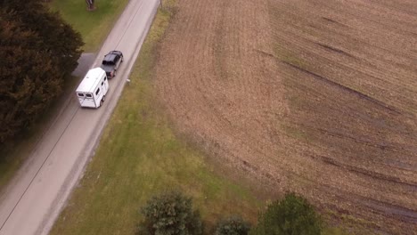 Pick-up-truck-hauling-white-horse-trailer-through-rural-Michigan-landscape
