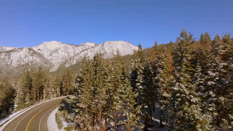 Aerial-of-road-winding-through-Lake-Tahoe-with-pan-right-to-landscape-of-Douglas-Fir-trees-and-mountains