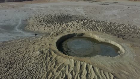 Aerial-Circle-Dolly-Around-Mud-Volcano-With-Mud-Pool-In-Crater