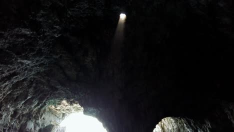 Mystical-atmosphere-inside-a-sea-cave-with-a-ray-of-light-coming-down-from-a-hole-in-the-ceiling,-Vis-island,-Adriatic-Sea,-Croatia