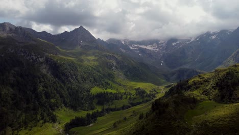 Drone-footage-from-the-Austrian-Alps-on-a-cloudy-summer-day,-lush-green-forests-and-hillside-can-be-seen