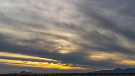 Ein-Goldener-Sonnenuntergang-Erscheint-An-Einem-Bewölkten-Tag-über-Der-Mojave-Wüstenlandschaft---Weitwinkel-Zeitraffer
