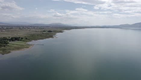 Video-Con-Un-Dron-Sobre-El-Lago-Skadar-En-Albania,-Descendiendo-Del-Cielo-Hasta-Alcanzar-El-Nivel-Del-Agua,-Sobrevolándolo