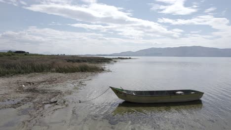 Video-with-a-drone-on-Lake-Skadar-in-Albania,-on-an-old-wooden-boat-in-the-foreground,-surpassing-it-in-different-planes-at-water-level