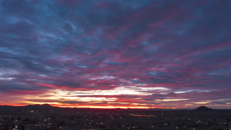 Aerial-hyper-lapse-over-California,-City-in-the-Mojave-Desert-during-a-brilliantly-colorful-sunrise-as-viewed-from-above-the-city