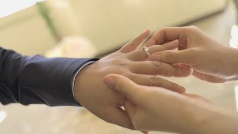 A-woman's-hand-slowly-puts-a-wedding-ring-on-a-man's-hand