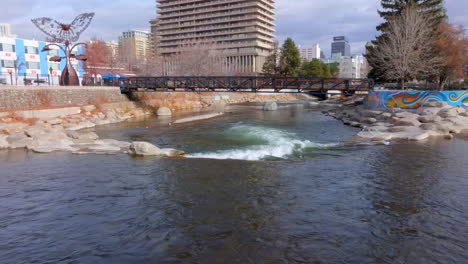 Push-over-rapids-and-towards-and-over-pedestrian-bridge-on-the-Truckee-River-in-downtown-Reno,-Nevada