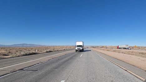 Highway-drive-through-the-Mojave-Desert-passing-a-truck-while-looking-out-the-rear-window