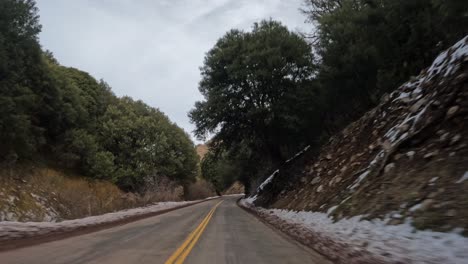 Conduciendo-A-Lo-Largo-De-Un-Camino-Sinuoso-En-Las-Montañas-Tehachapi-Durante-El-Invierno-Con-Nieve-En-El-Camino---Hiperlapso