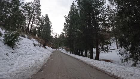Driving-along-a-winding-snowy-road-in-the-Tehachapi,-California-mountains-in-winter---forward-point-of-view