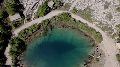 Video-Mit-Drohne-Eines-Flugzeugkrans,-Der-Zu-Einer-Vogelperspektive-über-Den-Cetina-see-In-Kroatien-Aufsteigt,-Wobei-Der-Fokus-Vom-Boden-Sehr-Nahe-Am-Wasser-Liegt