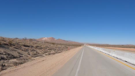 Blick-Aus-Dem-Heckfenster-In-Einem-Auto,-Das-Durch-Die-Trockene-Landschaft-Der-Mojave-Wüste-Fährt