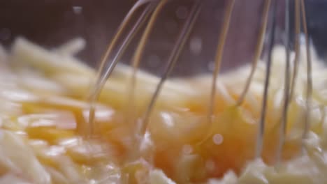 Mixing-Eggs,-Ham,-And-Grated-Cheese-In-A-Clear-Glass-Bowl-Using-A-Whisk