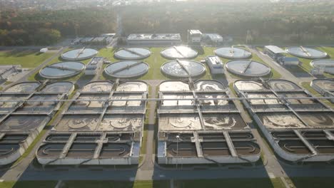Aerial-trucking-shot-over-the-huge-wastewater-treatment-plant-with-beautiful-sun-rays-and-flares