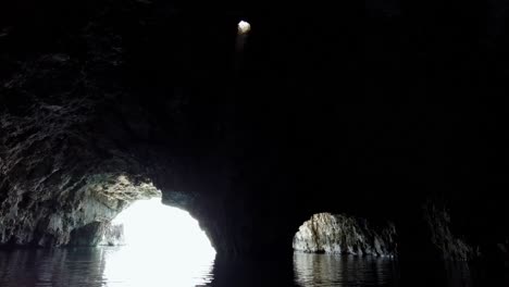 Unique-atmosphere-inside-a-sea-cave-with-a-ray-of-light-coming-down-from-a-hole-in-the-ceiling,-Vis-island,-Adriatic-Sea,-Croatia