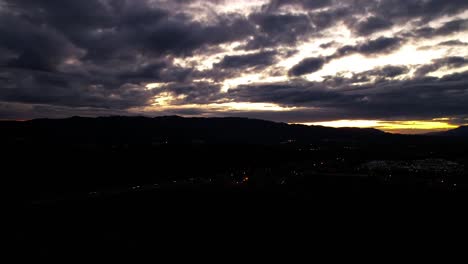 Aerial-drone-hyperlapse-Clouds-moving-over-mountain-silhouette-at-Sunset
