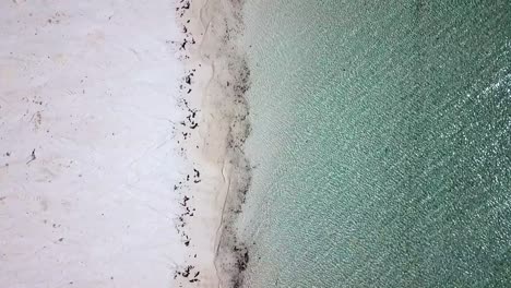 Erstaunliche-Vogelperspektive-Drohnenaufnahme-Von-Kristallklarem-Wasser-Der-Meereslinie