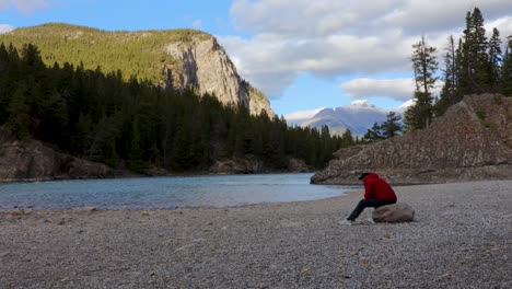 Hiker-wearing-a-red-jacket-relaxing-beside-a-mountain-river