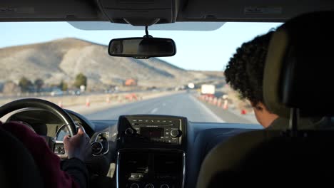 Teen-driver-passing-highway-construction-while-he-learns-to-drive---backseat-view-of-the-driver-and-teacher-in-slow-motion