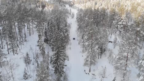 Vehicle-Driving-On-The-Snowy-Road-In-The-Forest-At-Daytime---aerial-drone-shot