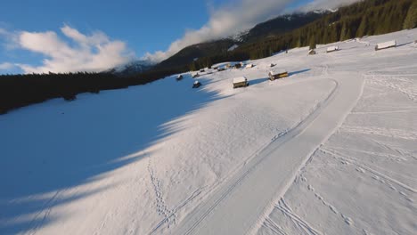 FPV-drone-shot-captured-in-Slovenia-in-Pokljuka-forest-with-surrounding-nature-and-mountains-at-golden-hour-at-sunset-with-fast-and-cinematic-movement-around-the-village-and-forest