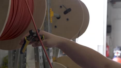 Cutting-electric-red-wire-from-a-spool-used-for-solar-panel-installation-with-a-cutting-tool,-Slow-motion-close-up-shot