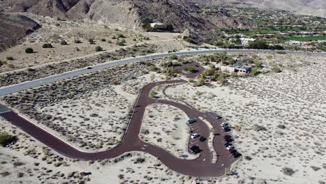 Car-parking-lot-on-highway-side-in-California-desert,-aerial-drone-shot