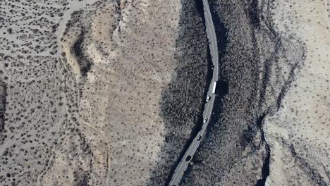 Cars-and-public-bus-driving-on-desert-highway-road,-aerial-top-down-shot
